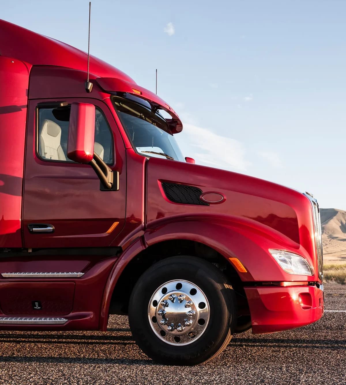 Red semi truck cab parked on a desert road